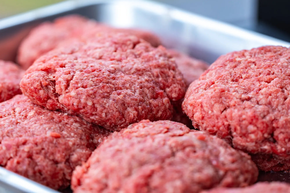 A tray of raw ground beef formed into burger patties.