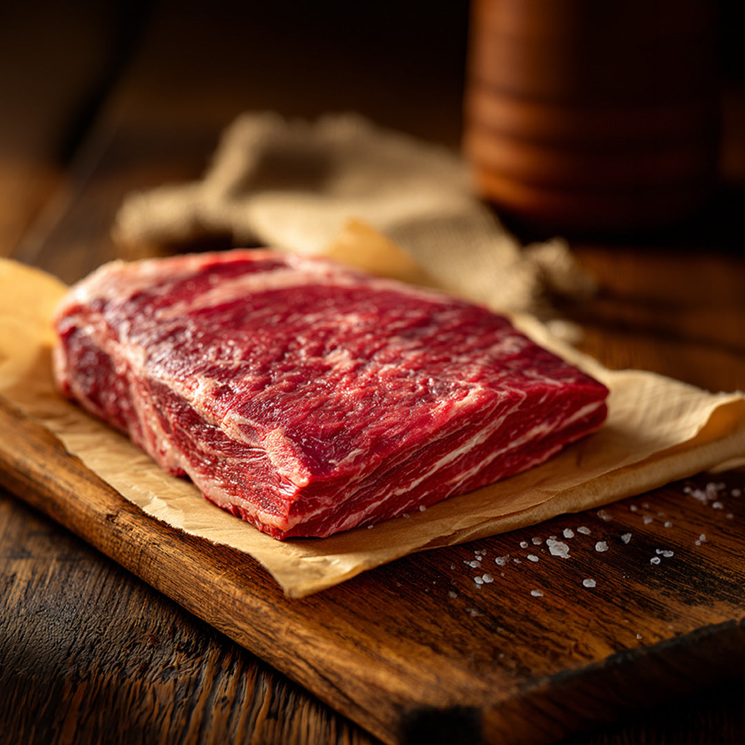 Raw beef on a wooden cutting board with a wooden background