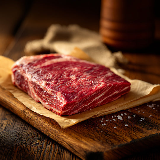 Raw beef on a wooden cutting board with a wooden background