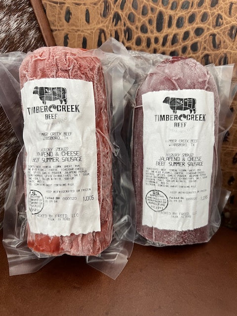 Two packages of Timber Creek Beef summer sausage on a textured surface.