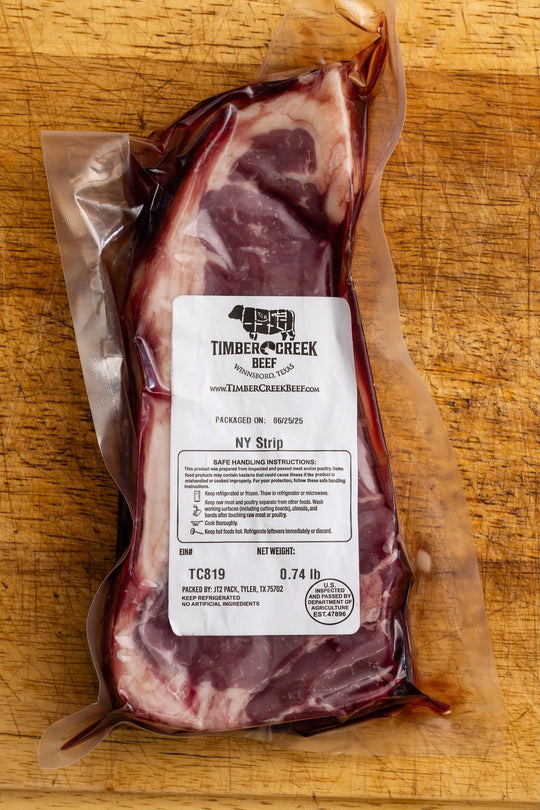 Raw NY Strip steak from Timber Creek Meats on a wooden surface