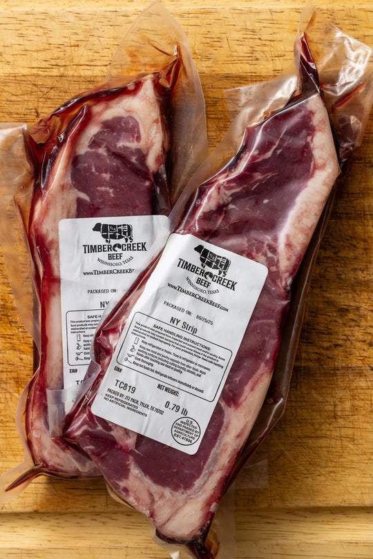Two packages of raw beef with labels on a wooden surface